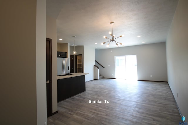 unfurnished living room featuring an inviting chandelier and dark hardwood / wood-style flooring