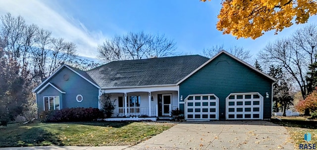 view of front of home with a garage, covered porch, and a front yard