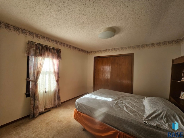 bedroom featuring light colored carpet, a textured ceiling, and a closet