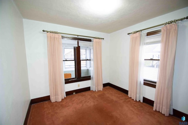 carpeted empty room featuring a textured ceiling