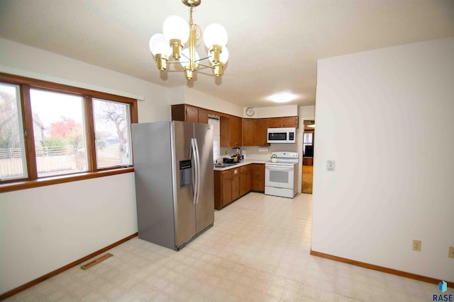 kitchen with an inviting chandelier, white appliances, and decorative light fixtures