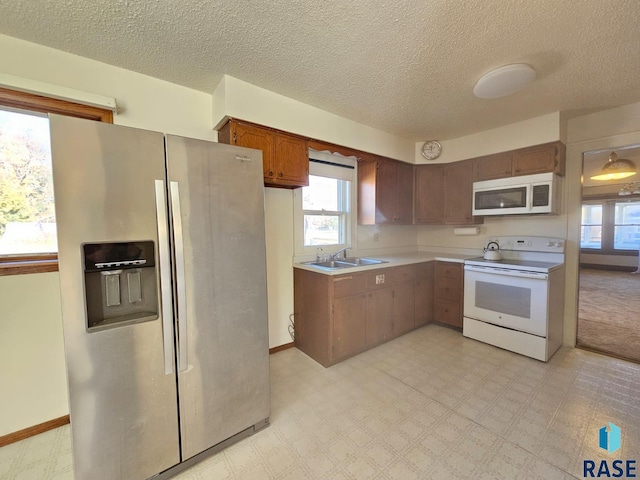 kitchen featuring white appliances, sink, and a textured ceiling