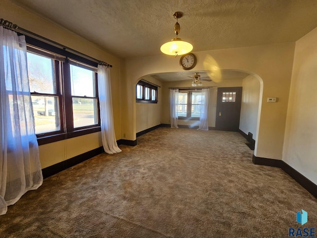 empty room featuring ceiling fan, a textured ceiling, and carpet floors