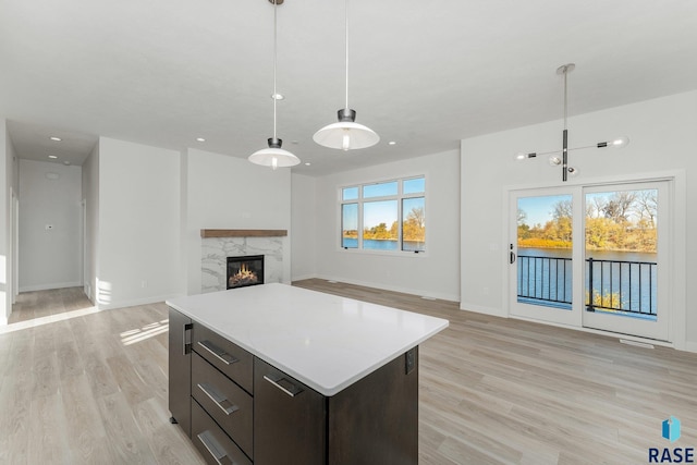 kitchen with a wealth of natural light, light hardwood / wood-style floors, decorative light fixtures, and a high end fireplace