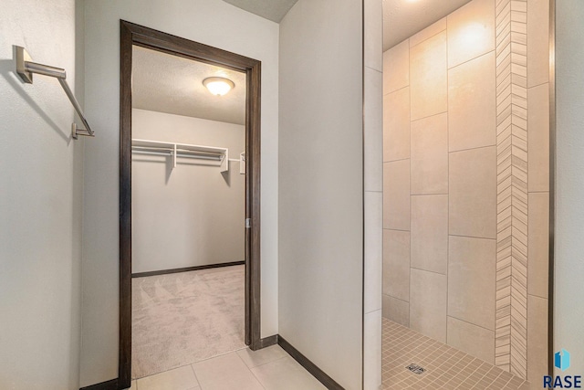 bathroom featuring tiled shower, a textured ceiling, and tile patterned floors