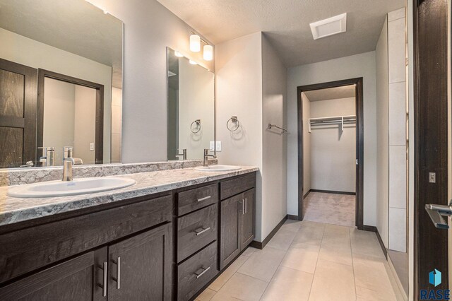 bathroom featuring tile patterned flooring, vanity, and a textured ceiling