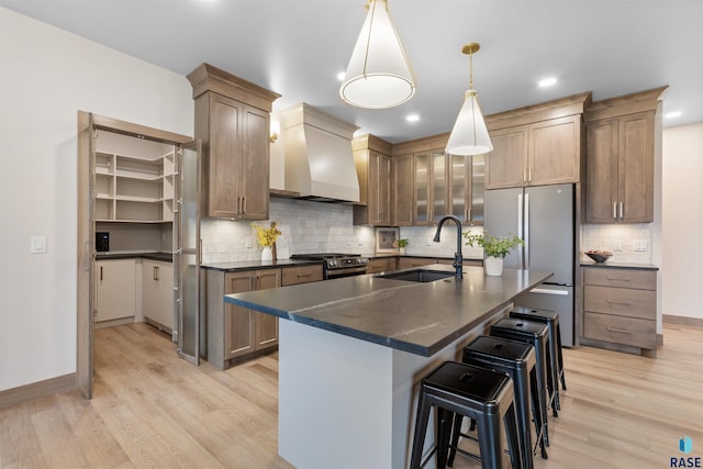 7309 E Shadow Pine Cir, Sioux Falls, SD 57110 - kitchen with a sink, appliances with stainless steel finishes, dark countertops, premium range hood, and light wood-type flooring