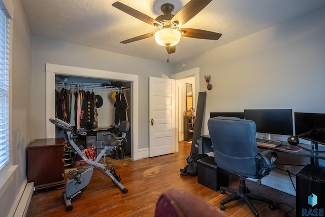 office with hardwood / wood-style floors, ceiling fan, a baseboard radiator, and a textured ceiling