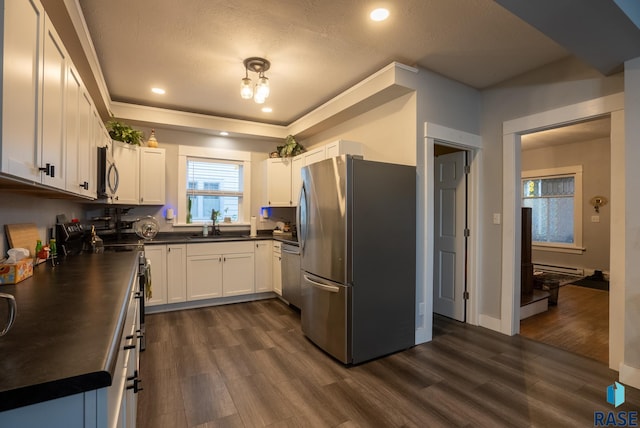 kitchen with dark wood-type flooring, white cabinets, a textured ceiling, sink, and appliances with stainless steel finishes