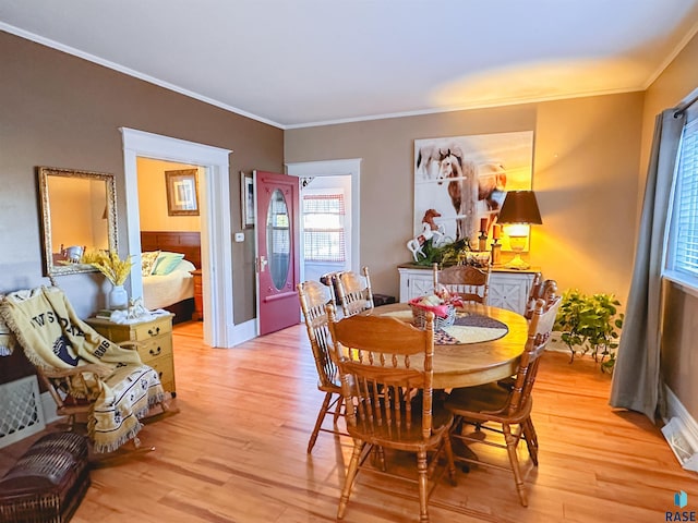 dining area with light wood-type flooring and crown molding