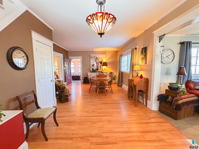 dining area with light wood-type flooring and ornamental molding