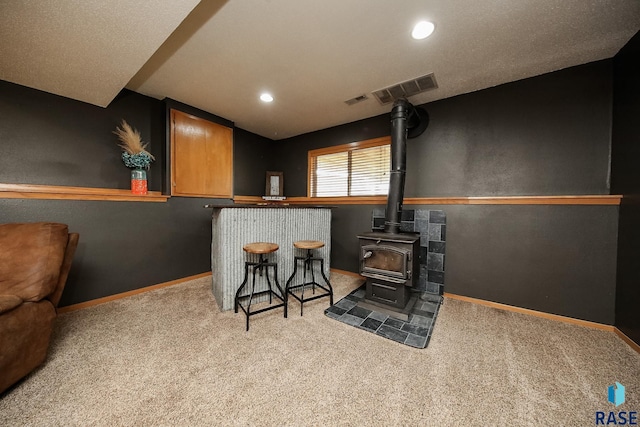 bar featuring light colored carpet and a wood stove