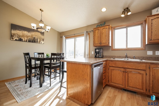 kitchen with light wood-type flooring, an inviting chandelier, sink, vaulted ceiling, and stainless steel dishwasher