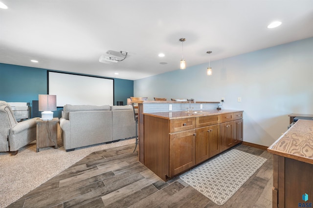 kitchen featuring sink, light stone countertops, a kitchen bar, decorative light fixtures, and dark hardwood / wood-style flooring