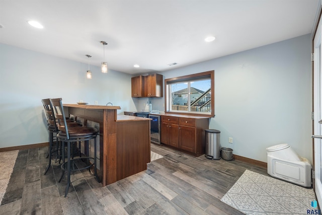 kitchen featuring dark hardwood / wood-style flooring, pendant lighting, a breakfast bar, and dishwasher