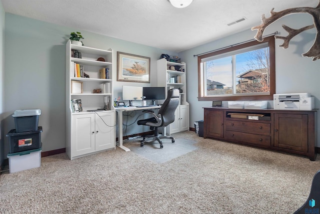 carpeted office featuring a textured ceiling