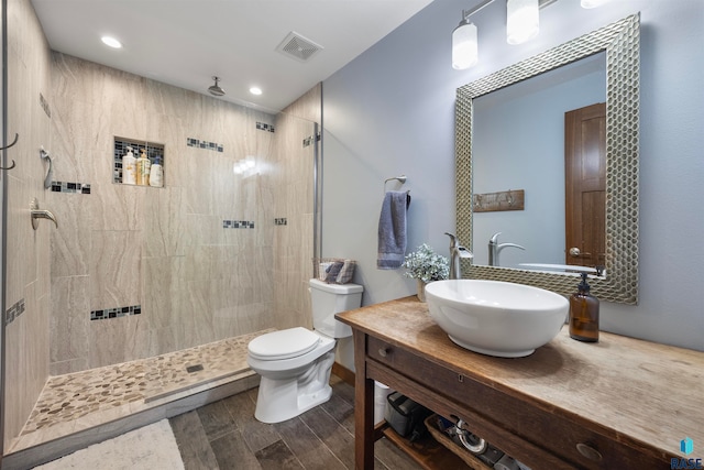 bathroom with toilet, vanity, hardwood / wood-style floors, and tiled shower