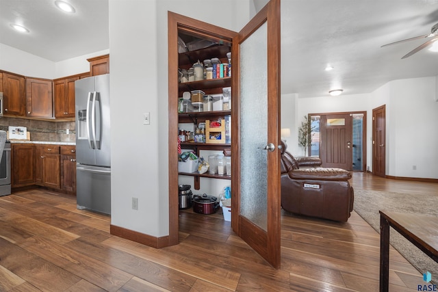 kitchen featuring stainless steel appliances, light stone countertops, ceiling fan, dark hardwood / wood-style floors, and decorative backsplash