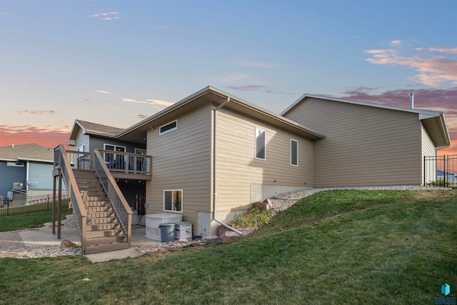 back house at dusk with a wooden deck and a yard