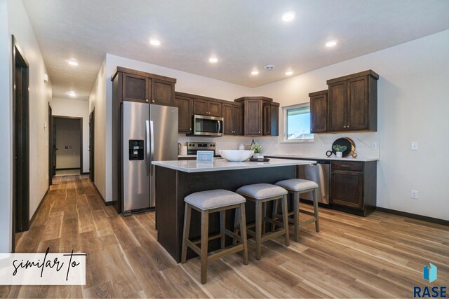 kitchen featuring a center island, hardwood / wood-style flooring, a breakfast bar, and stainless steel appliances