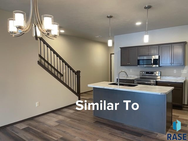 kitchen with stainless steel appliances, sink, a kitchen island with sink, and dark hardwood / wood-style flooring