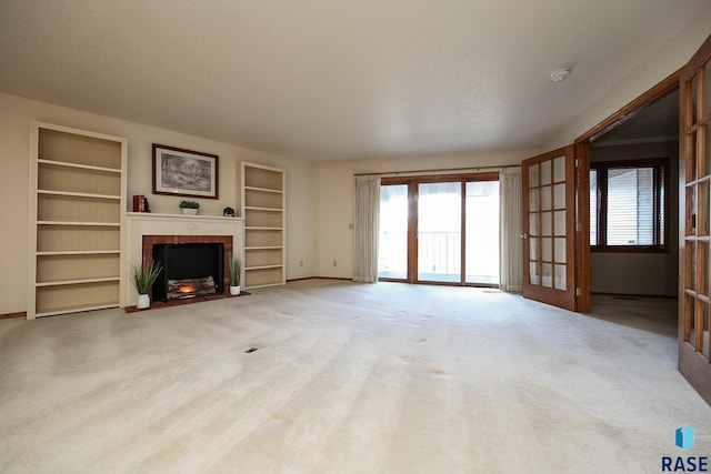 unfurnished living room with built in features, a brick fireplace, light colored carpet, a textured ceiling, and french doors