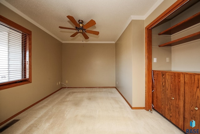 carpeted empty room with ornamental molding, ceiling fan, and a textured ceiling