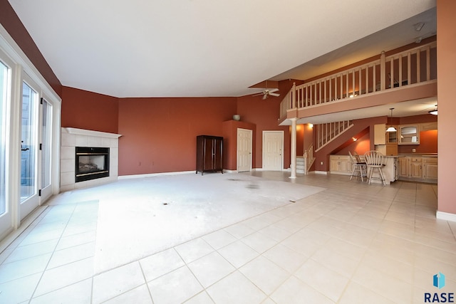 unfurnished living room featuring light tile patterned floors, high vaulted ceiling, ceiling fan, and a tiled fireplace