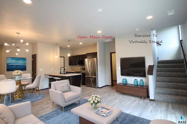 living room featuring an inviting chandelier, light hardwood / wood-style flooring, and sink