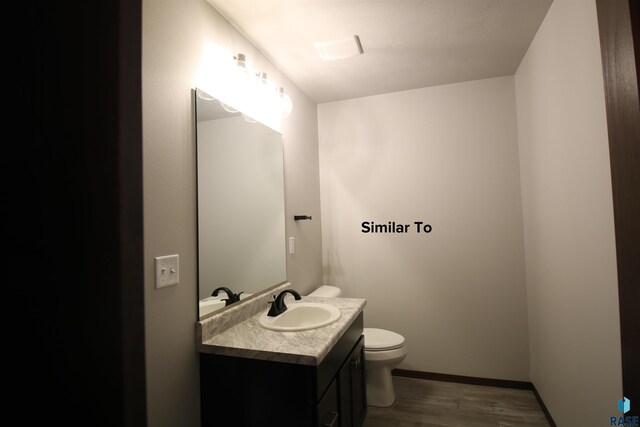 bathroom with toilet, vanity, and wood-type flooring