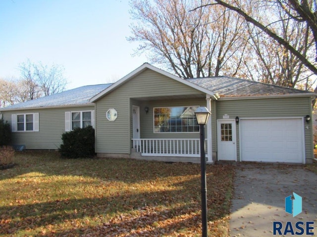 ranch-style house featuring a front lawn, a garage, and covered porch