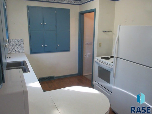 kitchen featuring dark wood-type flooring, sink, white appliances, and blue cabinets