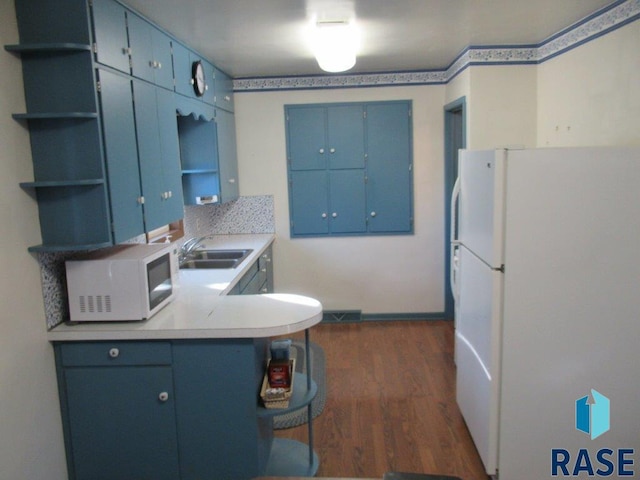 kitchen with blue cabinetry, white appliances, sink, and dark hardwood / wood-style floors