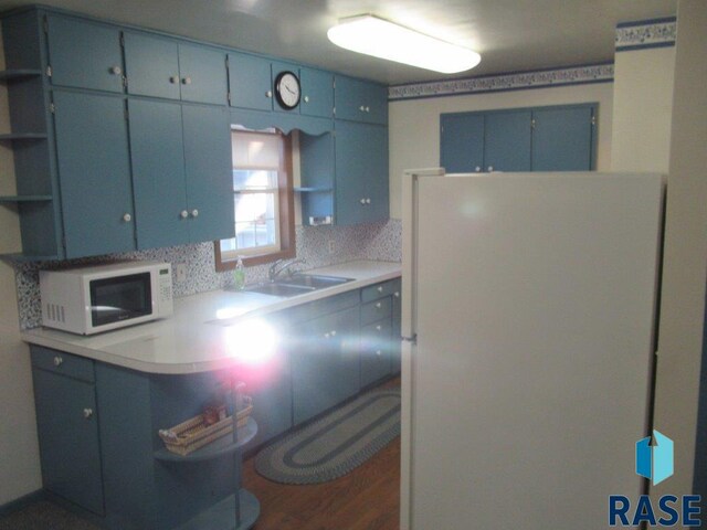 kitchen with blue cabinetry, tasteful backsplash, white appliances, and dark hardwood / wood-style floors