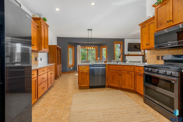 kitchen featuring stainless steel appliances, sink, light stone counters, kitchen peninsula, and pendant lighting