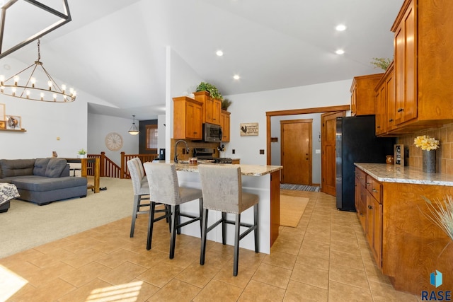 kitchen with stainless steel appliances, light colored carpet, light stone counters, and lofted ceiling