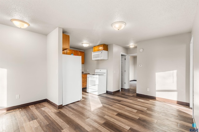 kitchen featuring a textured ceiling, hardwood / wood-style flooring, and white appliances