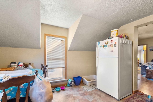 kitchen featuring lofted ceiling, a textured ceiling, and white fridge