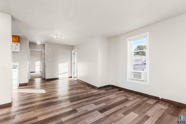 empty room with dark wood-type flooring, cooling unit, and a textured ceiling