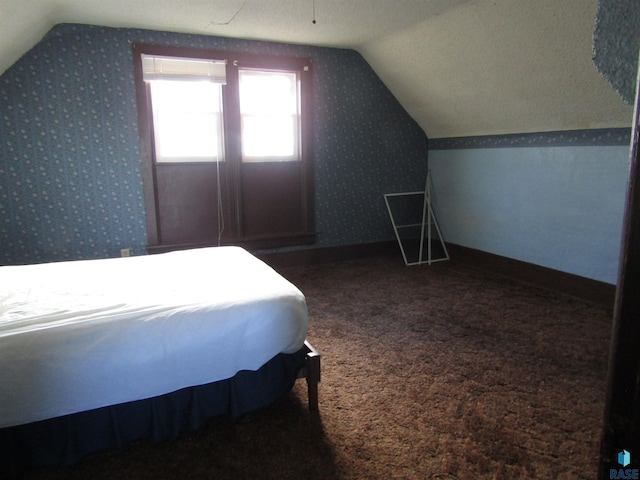 carpeted bedroom with vaulted ceiling and a textured ceiling