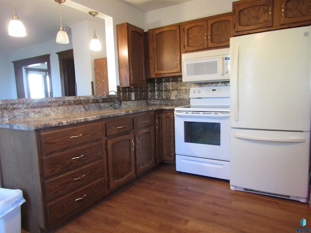 kitchen with tasteful backsplash, white appliances, dark hardwood / wood-style flooring, hanging light fixtures, and kitchen peninsula