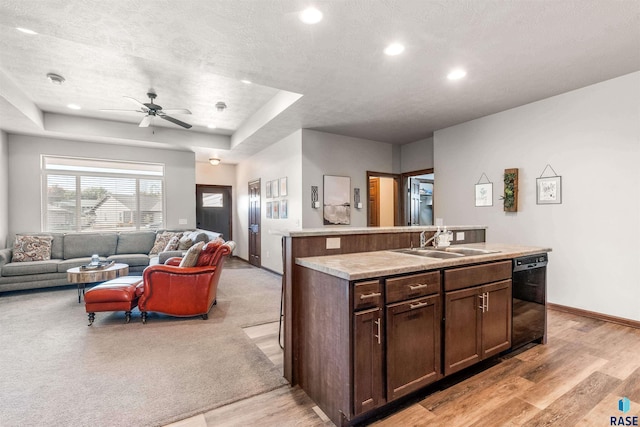 kitchen featuring light hardwood / wood-style floors, sink, a textured ceiling, an island with sink, and black dishwasher