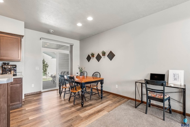 dining space featuring light hardwood / wood-style floors and a textured ceiling