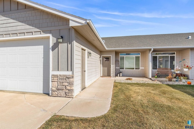 view of exterior entry featuring a garage and a yard