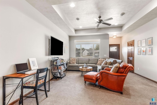 carpeted living room featuring a tray ceiling, a textured ceiling, and ceiling fan