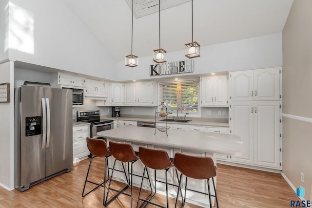 kitchen featuring a kitchen island, appliances with stainless steel finishes, sink, light hardwood / wood-style floors, and white cabinets