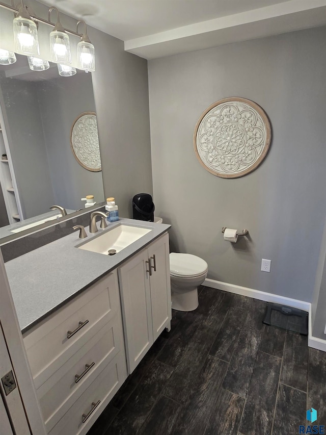 bathroom featuring toilet, vanity, and wood-type flooring