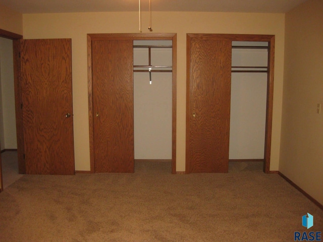 unfurnished bedroom featuring carpet flooring and multiple closets