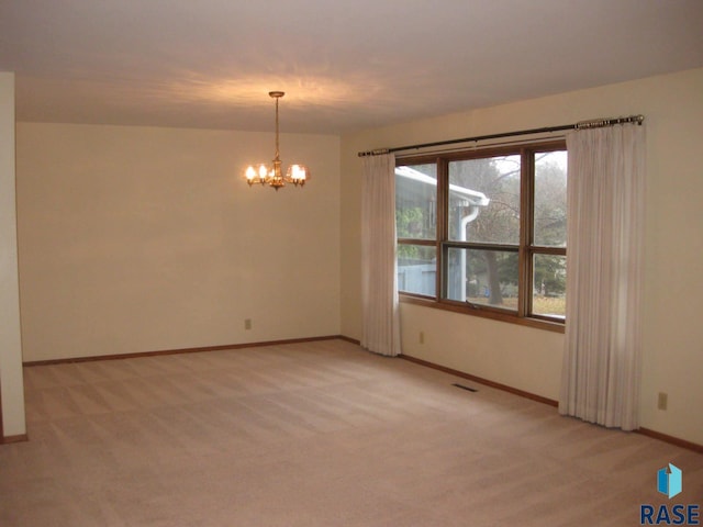 unfurnished room with light colored carpet and a notable chandelier