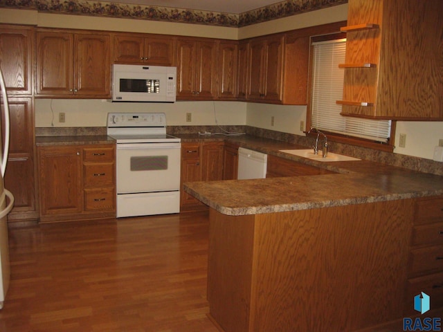 kitchen featuring kitchen peninsula, white appliances, sink, and dark hardwood / wood-style floors